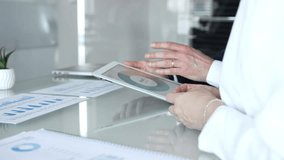 Business partners collaborating on financial data, discussing market trends, analyzing charts, and reviewing reports on a tablet in an office meeting setting - Powered by Shutterstock - Get 15% off with code: PIKWIZARD15