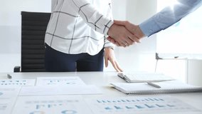 Business people shaking hands in office with financial charts, laptop and reports on desk top, symbolizing success, teamwork, agreement, collaboration and growth. Businesspeople handshake - Powered by Shutterstock - Get 15% off with code: PIKWIZARD15