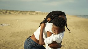 Joyful african american mother lifting and spinning happy son in warm embrace on sandy beach. Their loving bond evident as they laugh and play together by ocean during family trip - Powered by Shutterstock - Get 15% off with code: PIKWIZARD15