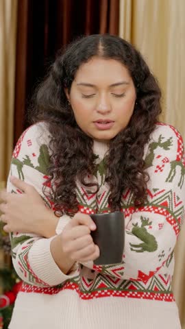 Vertical Video of Indian Woman Drinking Coffee while Feeling Cold with Christmas Tree in background