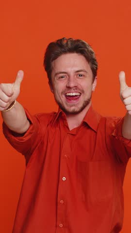 Happy joyful Caucasian man celebrating success victory, winning birthday, lottery jackpot goal achievement play game good positive news triumph. Young handsome guy isolated on orange studio background