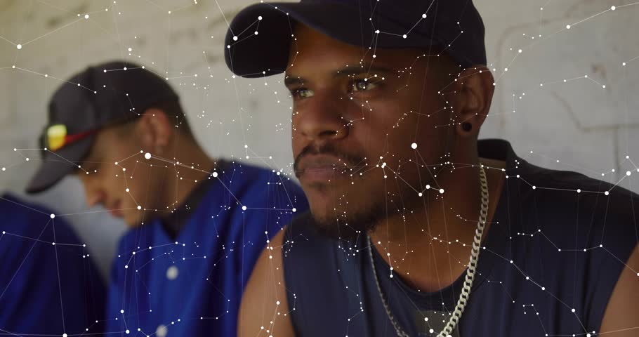 AR activating, foreground man shifting gaze for tech review with HUD panels overlaying readouts. Duo, teamwork, casual, worksite, wall, texture, grid