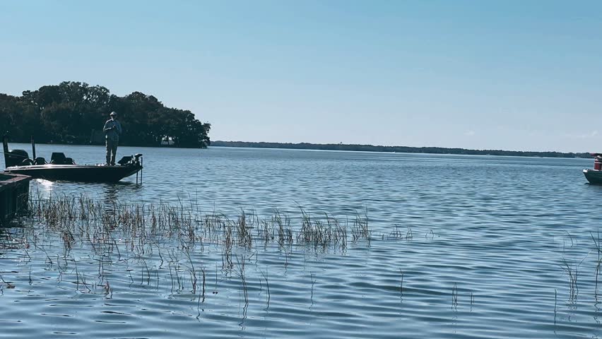 man fishing at a peaceful lake near a small fishing port on a warm sunny day with clear bright skies