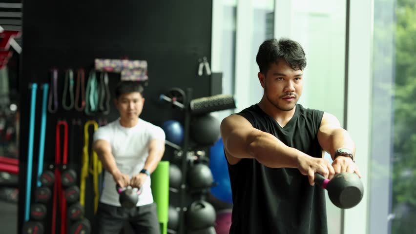 Two men perform kettlebell swings in a bright gym, surrounded by modern fitness equipment. - Powered by Shutterstock - Get 15% off with code: PIKWIZARD15