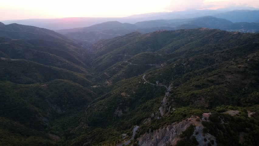 Bright green mountain slopes and dramatic gorge illuminated by sunset in Greece