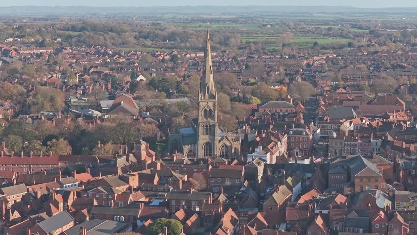 Newark on Trent cityscape with St. Mary Magdalene church spire rising above red brick rooftops, stretching to verdant countryside under a clear sunny sky