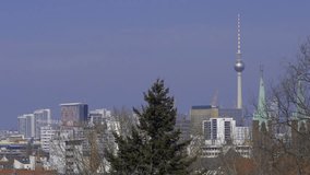 Fernsehturm tower stands above Berlin skyline as soft winter light reveals rooftops, modern buildings, and distant spires creating bright wide city view framed by bare trees in calm clear air. - Powered by Shutterstock - Get 15% off with code: PIKWIZARD15