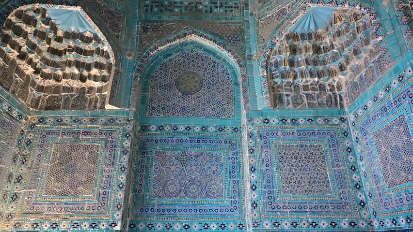 Vertical pan showing the ornate blue-tiled mausoleums of Shah i Zinda in Samarkand, Uzbekistan, under bright daylight.