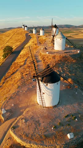 Aerial view of the historic windmills of Consuegra at sunrise, Castilla-La Mancha, Spain. Old historic windmills of Don Quixote character on the hills in morning light. Molinos de Viento de Consuegra