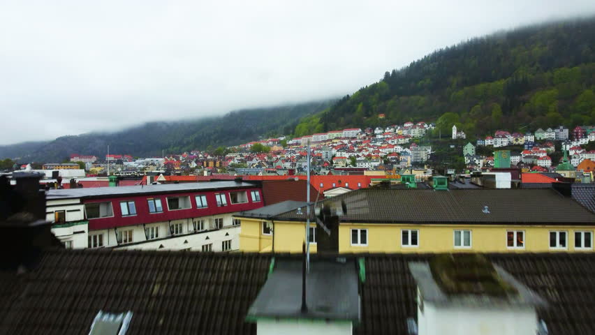Aerial view rising over buldings, revealing the Bryggen wharf, dark day in Bergen