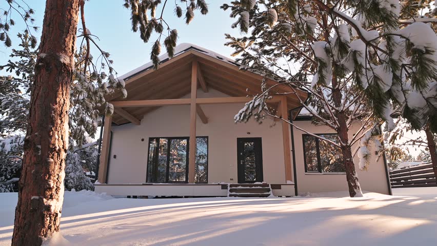 Modern house in a snowy landscape. Trees frame the facade