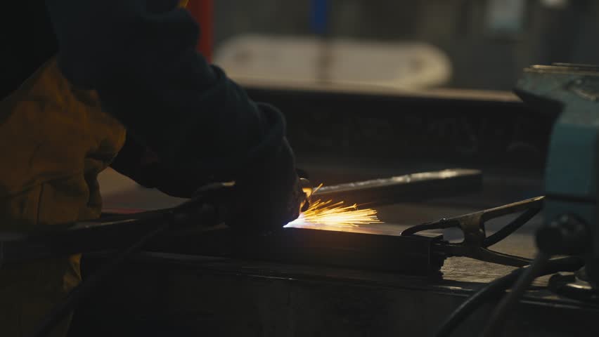 Worker Welding Metal Piece with Blue Sparks