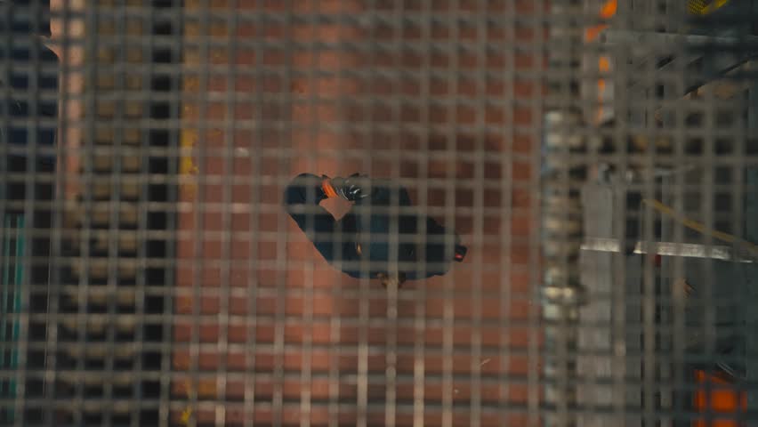 Female Maintenance Worker Seen From Above Through Industrial Floor Grid
