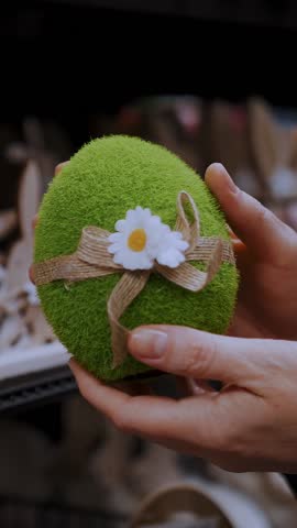 Easter fair. close-up. female hands holding a figurine of a funny green Easter egg. traditional european easter decor and decorations. Easter shopping, display in a store.