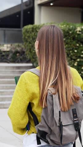 Happy university female blond student walking towards college building
