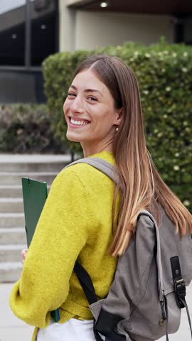 Happy university female blond student walking towards college building