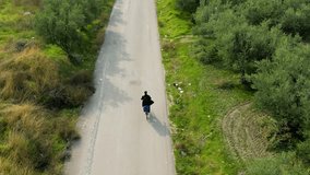 Cyclist in Black Riding on a Tree-Lined Asphalt Road Followed by a Drone – Scenic Outdoor Aerial Footage - Powered by Shutterstock - Get 15% off with code: PIKWIZARD15