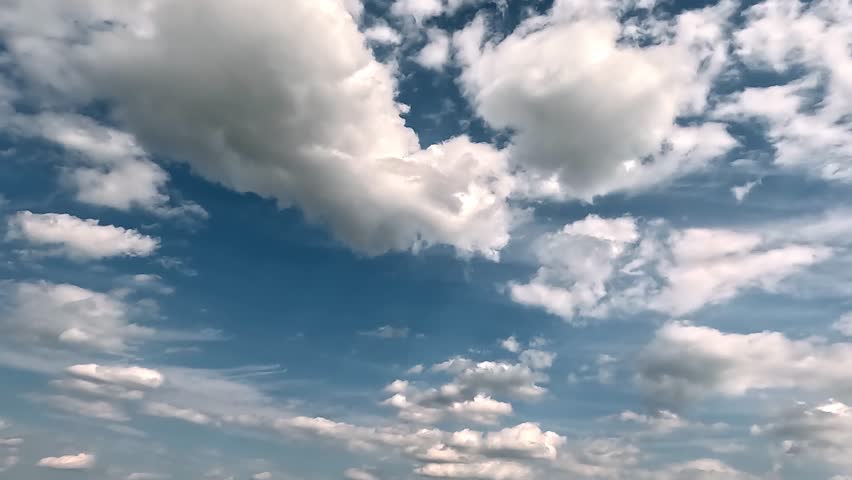 Fluffy clouds in the blue skies mooving forward. 4K video (Ultra High Definition) of cloudscape. Sky and clouds Timelapse. Sun shines through the clouds on the blue sky background.