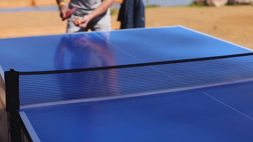 Ping-pong game, group of friends playing ping pong in a park,  play table tennis, family game in the backyard, colleagues teammates during competition at work, racket and ball on a blue tennis table