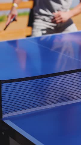 Ping-pong game, group of friends playing ping pong in a park,  play table tennis, family game in the backyard, colleagues teammates during competition at work, racket and ball on a blue tennis table