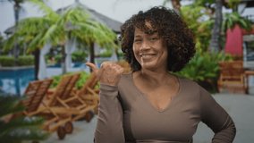 Woman smiles with hand on hip under palm trees by sunlit poolside at lush tropical resort; vacation escape serenity. - Powered by Shutterstock - Get 15% off with code: PIKWIZARD15