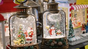 Person choosing Christmas snow globe lantern decoration in store - Powered by Shutterstock - Get 15% off with code: PIKWIZARD15