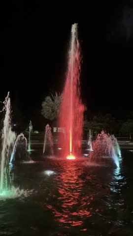 Beautiful water fountain at night illuminated with colorful lamps