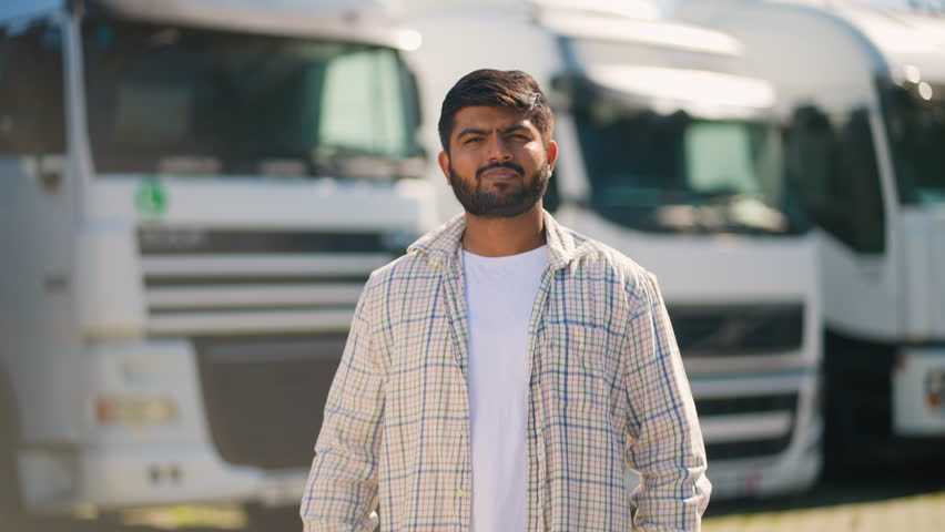 Confident Indian truck driver standing with arms crossed