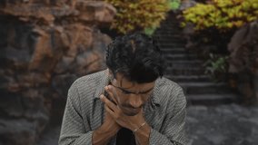Man with hand on neck experiencing tension near rocky forest stairs and moss covered rocks; discomfort strain. - Powered by Shutterstock - Get 15% off with code: PIKWIZARD15