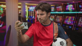 Man taking a selfie with smartphone while holding a soccer ball in a casino building; excitement fan pride. - Powered by Shutterstock - Get 15% off with code: PIKWIZARD15