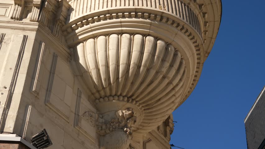 Beautiful limestone building facade in France, architectural element under the corner balcony