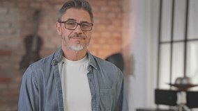 Portrait of happy confident casual middle aged man at home in loft room. Fit and healthy active senior male with grey hair looking at camera, smiling. Smart older guy in denim shirt. - Powered by Shutterstock - Get 15% off with code: PIKWIZARD15