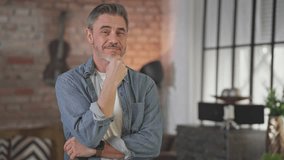 Portrait of happy casual middle aged man standing at home arms crossed in loft living room. Senior male with grey hair in denim shirt looking at camera, smiling, thinking. - Powered by Shutterstock - Get 15% off with code: PIKWIZARD15
