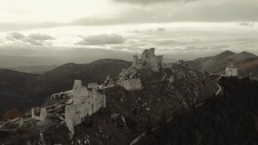 Cinematic drone shot of the ancient fortress of Rocca Calascio surrounded by the mountains of Abruzzo, Italy. Scenic hiking trail leading to the medieval castle on a rocky ridge at sunset. - Powered by Shutterstock - Get 15% off with code: PIKWIZARD15