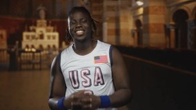 Man puckers lips in usa basketball jersey with american flag patch, bare shoulders visible inside catholic church nave; community playful joy. - Powered by Shutterstock - Get 15% off with code: PIKWIZARD15