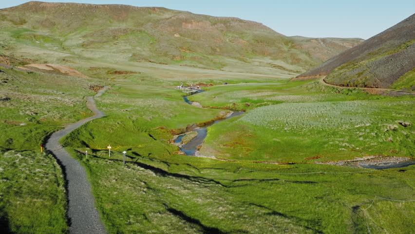 Tourists taking Hot Spring Thermal baths in Iceland. Trail leading up the Reykjadalur Valley to a natural hot spring located within grand natural beauty.