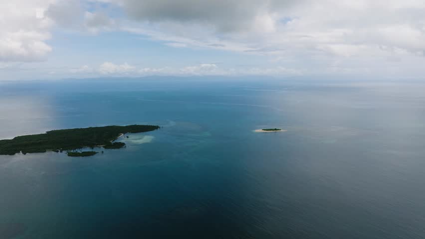 Wide seascape with scattered islands and cloudy blue sky over water. Siargao, Philippines.
