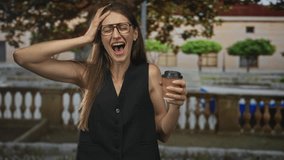 Woman holding takeaway coffee cup and raising hand near stone balustrade in front of building; commuter morning routine skepticism. - Powered by Shutterstock - Get 15% off with code: PIKWIZARD15