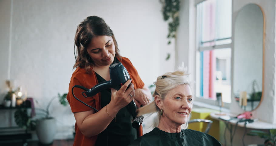 Mature woman, hairdresser and blow with hairdryer in beauty salon for haircare or style. Female person, customer and styling with brush or grooming hair for blowout, cosmetics or treatment in parlor