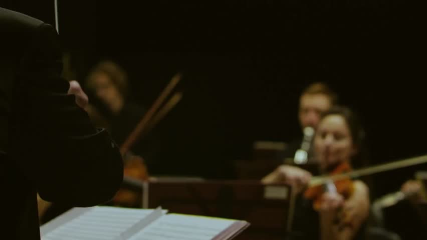 A conductor directing an orchestra with a baton, demonstrating musical leadership, performance, and orchestral coordination in action.