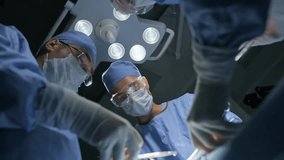 Low-angle shot of surgical care practitioners operating on an unconscious patient in a sterile operating room with overhead lights. - Powered by Shutterstock - Get 15% off with code: PIKWIZARD15