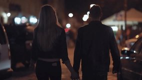 Young couple holding hands walking through the city at night, enjoying nightlife, heading to a party or concert, capturing love and fun moments. - Powered by Shutterstock - Get 15% off with code: PIKWIZARD15