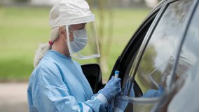 Medical technician in protective gear walks toward camera at mobile coronavirus testing station, showcasing pandemic response, safety measures, and healthcare service. - Powered by Shutterstock - Get 15% off with code: PIKWIZARD15