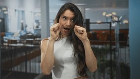 Woman raises clenched fists by cheeks with pouting lips in a dimly lit restaurant; sadness loneliness. - Powered by Shutterstock - Get 15% off with code: PIKWIZARD15