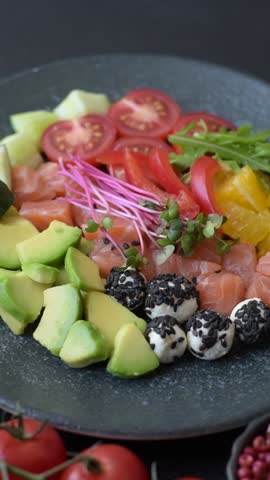 Bowl with salmon pieces, cheese, tomatoes, peppers and avocado. Salmon bowl as a food background for your design