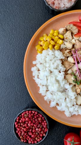 Bowl with chicken pieces, rice, tomatoes, peppers and microgreens. Bowl with chicken