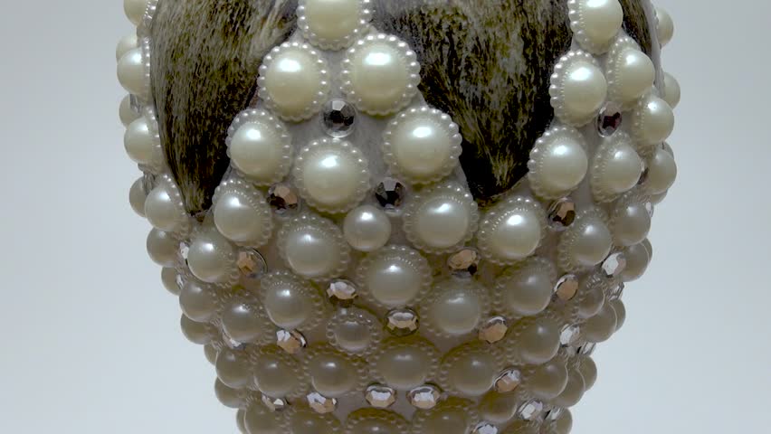 A close-up of a vase with rhinestones and pearls