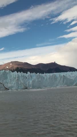 Witness stunning beauty of glaciers in Patagonia Andes as they tower over glacial lake, reflecting vibrant sky and surrounding mountains. Experience nature