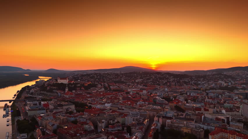 Amazing orange sunset sky over the mountain range. Scenery of old town of Bratislava, Slovakia. Aerial view.