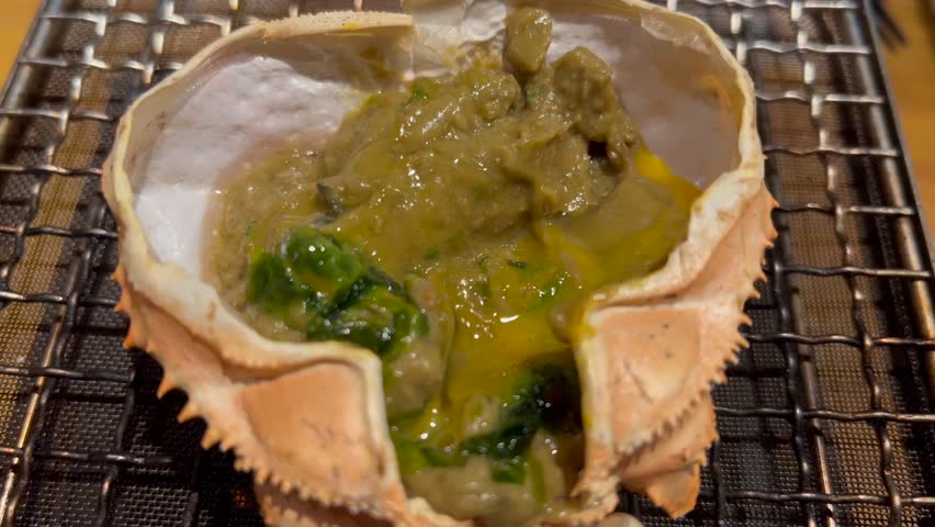 Crab miso baked in its shell, simmering on the grill.